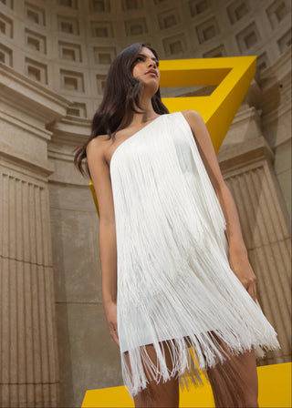 Woman in a white fringe dress standing in front of a classical architecture building with a yellow geometric sculpture.