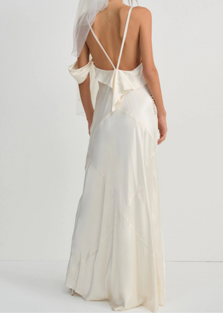 Woman wearing a white wedding dress with a sheer back and veil on a white background