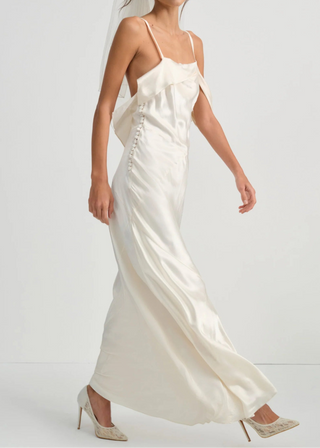 Woman wearing a white wedding dress with a veil on a plain background