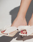 White sandals with ruffles worn by a person on a light background