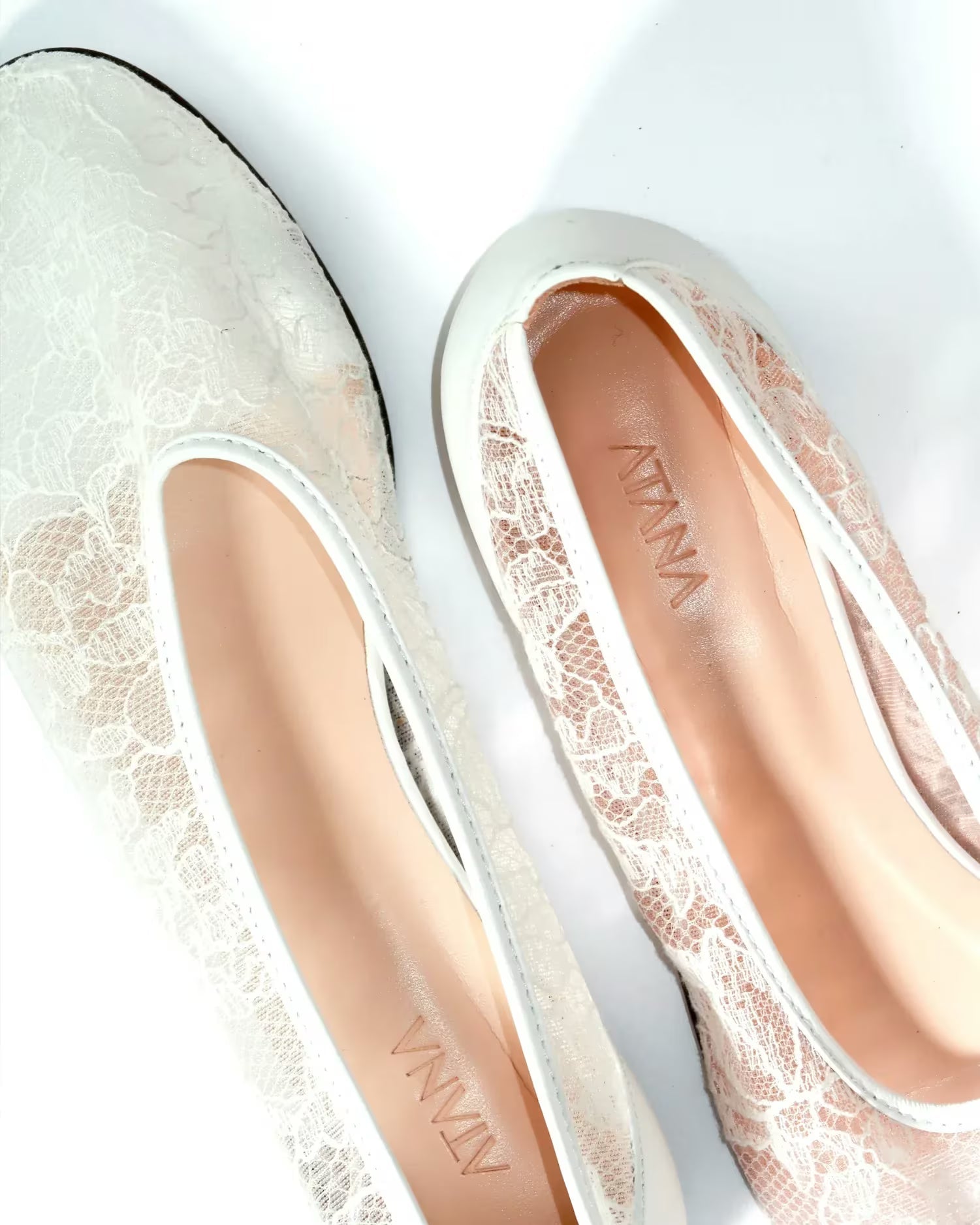 Pair of white lace shoes with atana branding on a light background