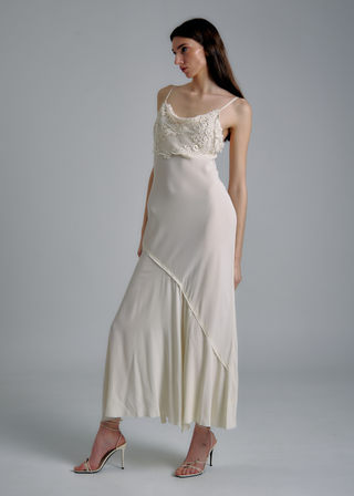 Woman wearing a white dress with an embroidered top on a gray background