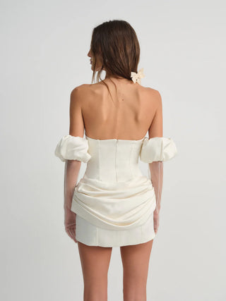 Woman wearing a white strapless dress with puff sleeves on a light gray background - serene mini dress