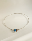 Silver necklace with a blue pendant on a light beige background