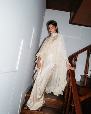 Woman in a white saree standing on a staircase