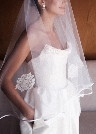 Woman wearing a white wedding dress with a veil in a softly lit room.