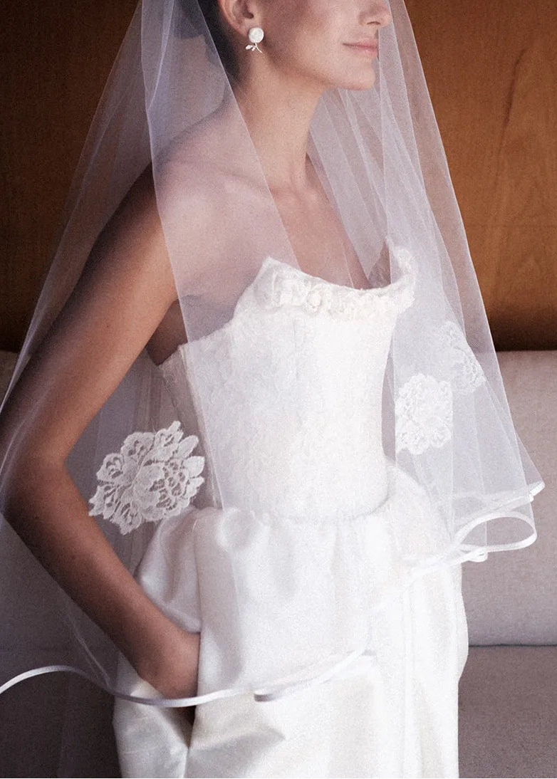 Woman wearing a white wedding dress with a veil in a softly lit room.
